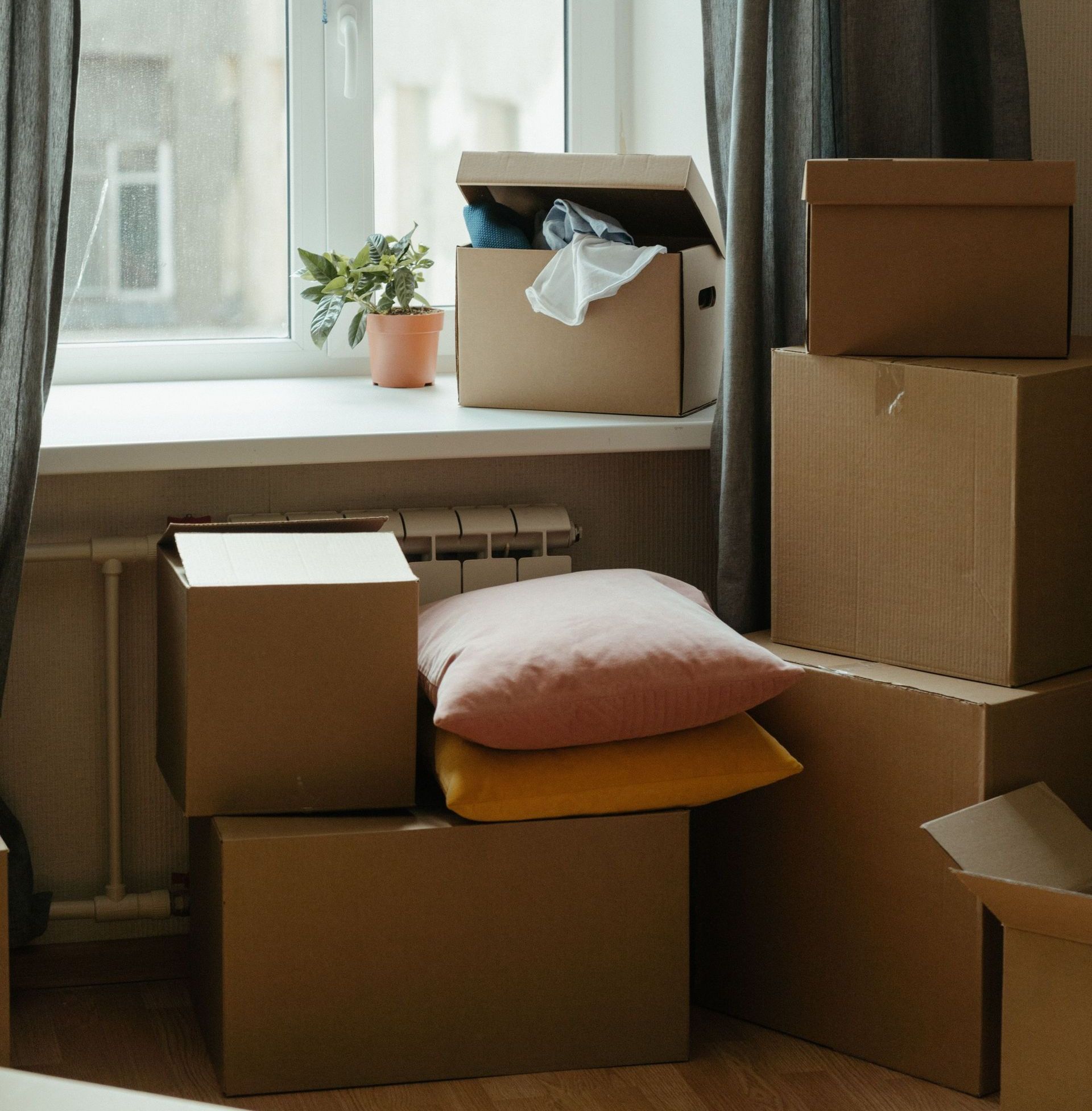 Stack of moving boxes in a sunlit room, symbolizing a fresh start in a new apartment.